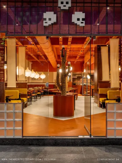 **Tres Amigos Restaurant, Ahmedabad:** This entrance shot captures the immersive cultural experience we designed for this Mexican restaurant. The vibrant color palette, custom lighting, and central cactus sculpture immediately set a warm, inviting tone, showcasing our ability to translate a brand's essence into a physical space.