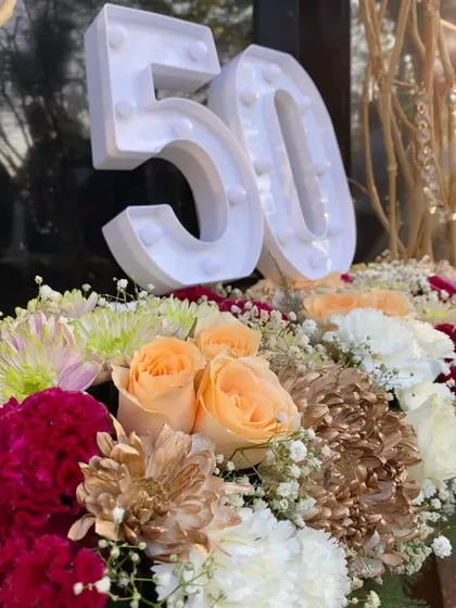 A close-up of the floral centerpiece, showing the mix of peach roses, deep red carnations, and textured chrysanthemums.