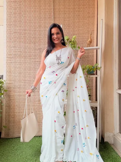 A simple white khadi cotton saree with colorful embroidered butis. It's a delicate and elegant piece that is perfect for a subtle, graceful look.