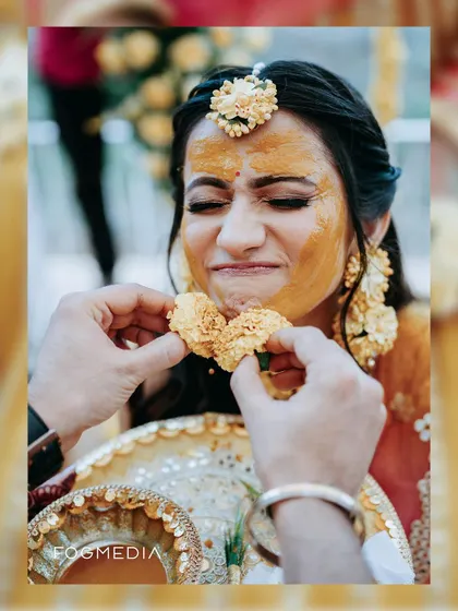A close-up of the bride playfully being fed sweets during her Haldi, capturing a fun and candid moment.