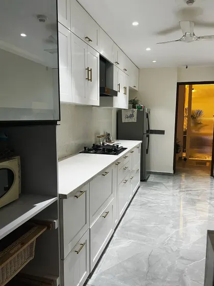 Another angle of the Noida kitchen, showing the placement of the refrigerator and the tall pantry unit, ensuring plenty of storage.
