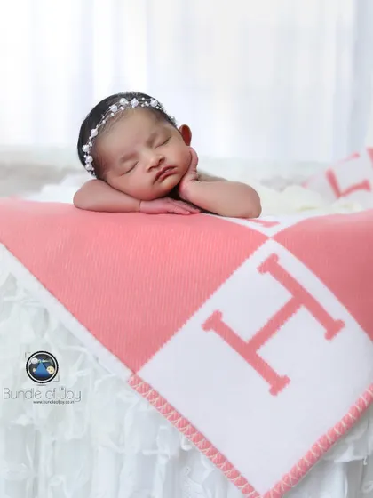 A simple and elegant portrait of a baby resting her head on her hands, lying on a personalized monogrammed blanket.