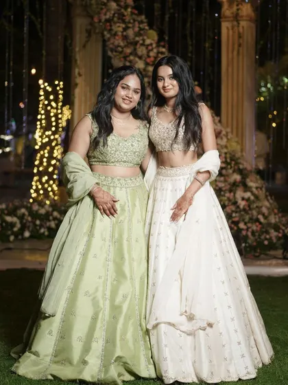 Another beautiful shot of our clients in their coordinated lehengas, standing before a stunning floral backdrop. Their smiles say it all.