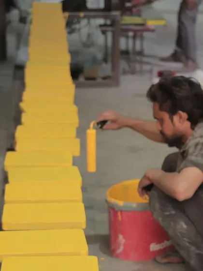A duplicate of image 68, showing an artisan painting yellow blocks.
