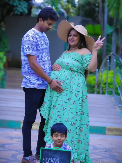 A fun family maternity photo with the older brother holding a "Coming Soon" sign, all dressed in matching casual wear.