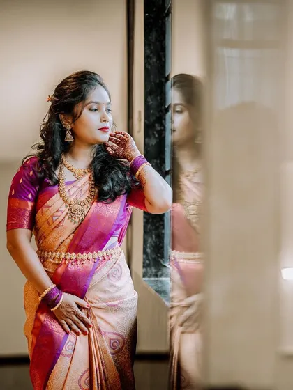 An elegant bridal portrait, with the bride looking out a window, her reflection captured softly in the glass.