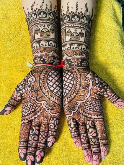Symmetrical bridal mehndi that covers both hands up to the elbows. The design includes traditional elements like paisleys, hearts, and architectural domes for a classic bridal look.