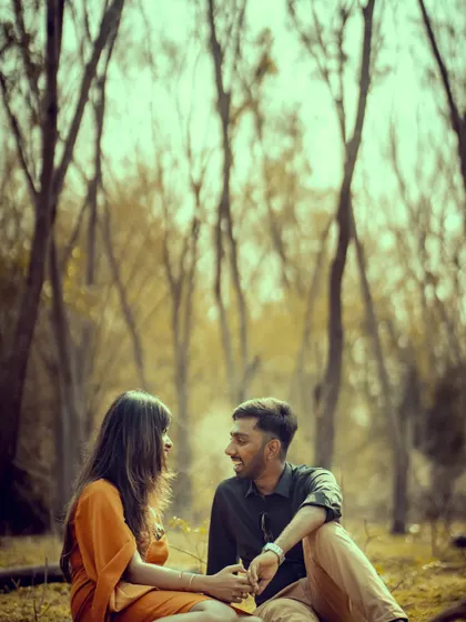 A candid moment of conversation and laughter during a pre-wedding shoot in a rustic, wooded area.