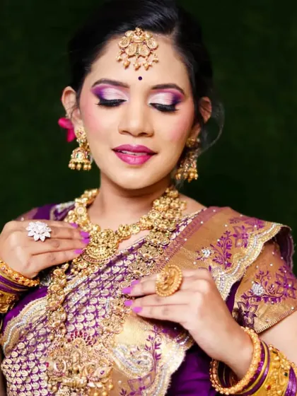 This bride's look is all about regal elegance. The purple and gold tones in her makeup perfectly match her saree, and the layered necklaces complete the look.