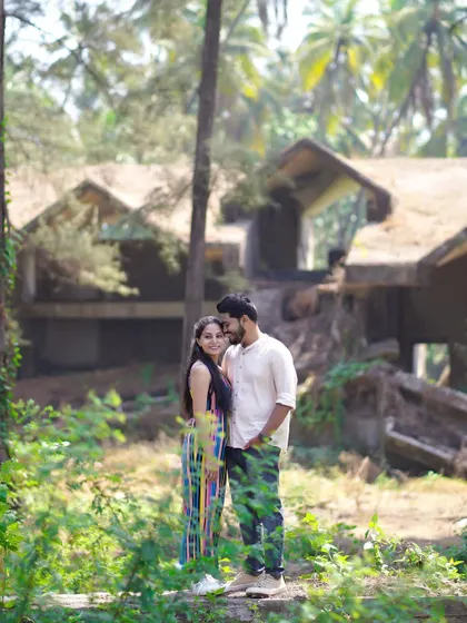 A portrait in a lush, green setting near the beach. The abandoned building in the background adds a unique, rustic element to the shot.