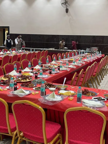 A long view of the dining area before guests are seated. The red chairs and matching tablecloths provide a classic and elegant look for a wedding reception.