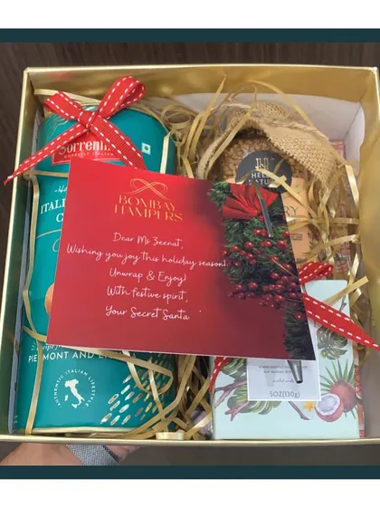 A peek inside a cozy Secret Santa hamper for the holiday season. It features Italian cookies, gourmet snacks, and a personalized note to spread festive cheer.