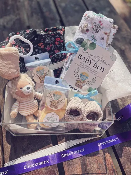 Another angle of the acrylic box hamper, highlighting the soft booties and personalized card, ready to be gifted to the new parents.