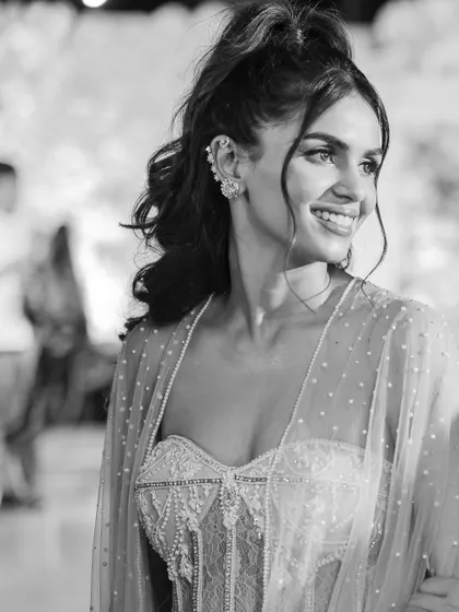 A beautiful black and white portrait of Manisha, capturing her happy expression and the delicate details of her mehendi gown and ear cuffs.
