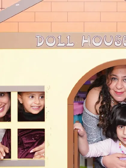 A family peeks out from the windows of our charming pretend-play dollhouse.