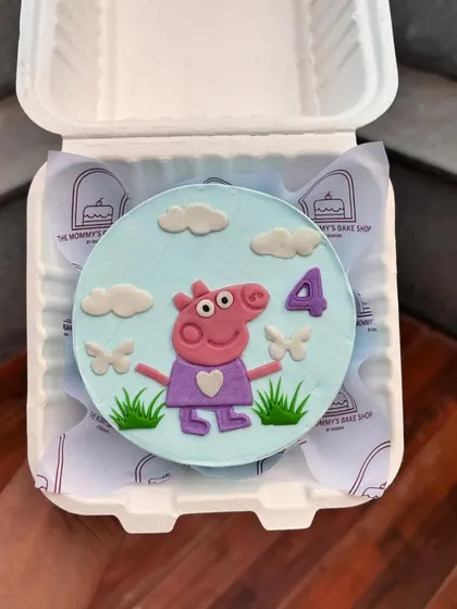 A sweet Peppa Pig bento cake for a fourth birthday. The design features Peppa, clouds, and grass, all crafted from fondant on a sky-blue base.