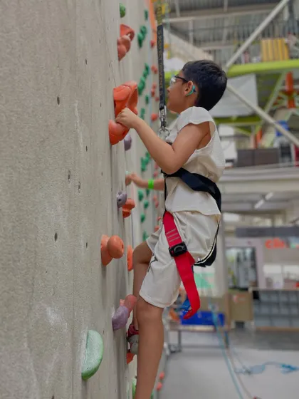 A young boy in full gear focuses intently on his climb. We provide all the necessary equipment, including harnesses and shoes, to ensure a safe and enjoyable experience.