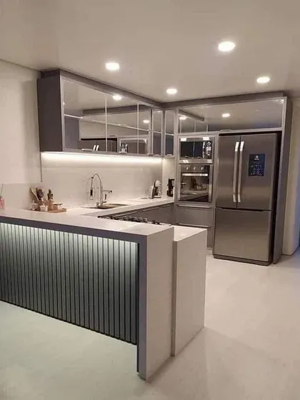 I love the sleek look of this kitchen, with its mirrored upper cabinets and under-counter lighting. The breakfast bar is seamlessly integrated into the design, creating a perfect spot for a quick coffee.