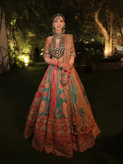 A full-length portrait displaying the vibrant colors and intricate details of her Rimple and Harpreet bridal lehenga. The entire look is a masterpiece of color, craft, and beauty.