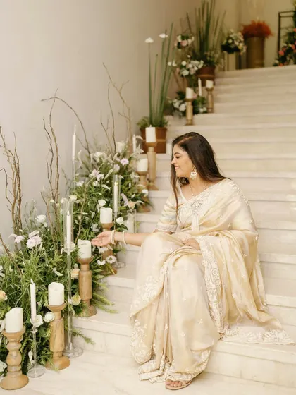 The birthday girl enjoying the beautiful decor we set up for her milestone celebration. The staircase is adorned with fresh white and green florals and wooden candle holders for a rustic yet elegant feel.