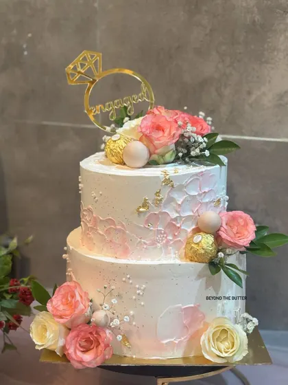 This angle shows the beautiful texture and floral arrangement on this two-tier pink and white cake, perfect for any happy celebration.