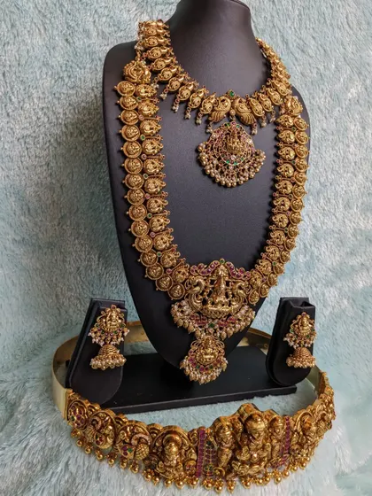 This is a classic Kaasina Sara set, featuring a coin haara and a matching choker with peacock and Lakshmi designs. It's a complete, regal look for a South Indian bride.