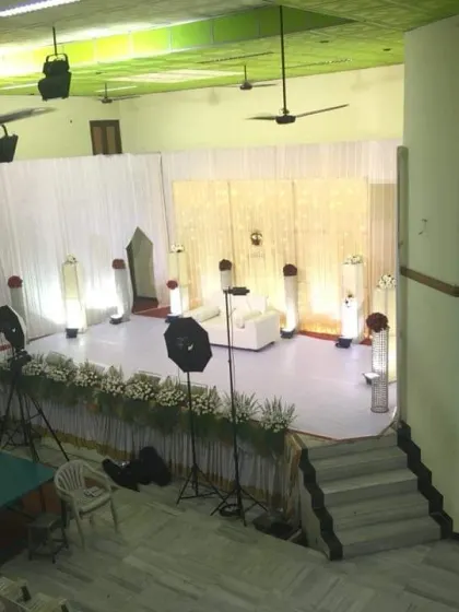 A wide-angle shot of the hall, showing the minimalist white stage and professional lighting setup.