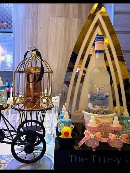 A whimsical bar setup for a baby shower. We used decorative elements like a miniature tricycle and baby bottles to hold shots, creating a playful and memorable theme.