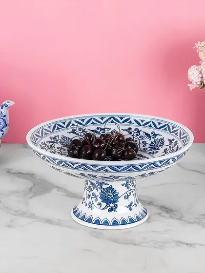 This elevated serving bowl in blue pottery is perfect for presenting fruits or desserts. The classic floral pattern and sturdy base make it a beautiful and functional piece for any occasion.