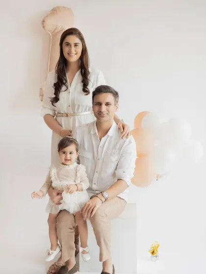A classic family portrait for a first birthday. The clean, minimalist setup ensures that the family's happy connection is the star of the show.