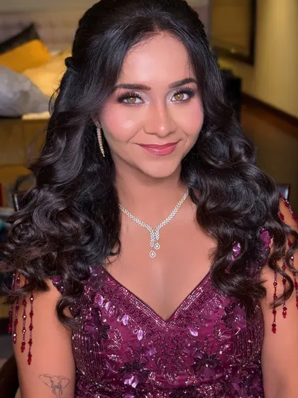 A beautiful reception look with soft makeup and voluminous curls. The focus is on her bright eyes and radiant smile.