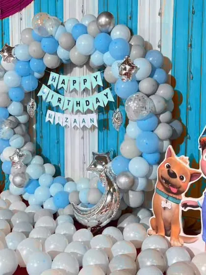A Cocomelon themed ring decoration in shades of blue and silver, with character cutouts and a floor covered in balloons for a fun, playful atmosphere.