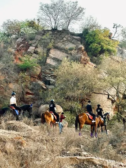 Our riders navigate a path along the base of a beautiful rock formation. The natural beauty of the Aravalis is the true star of our horseback safaris.