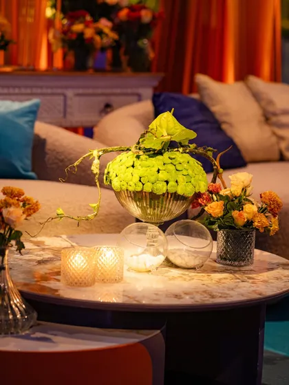 A unique centerpiece featuring a globe of bright green chrysanthemums, adding an unexpected pop of color to the orange and blue theme. We love to play with color to create surprising and delightful compositions.