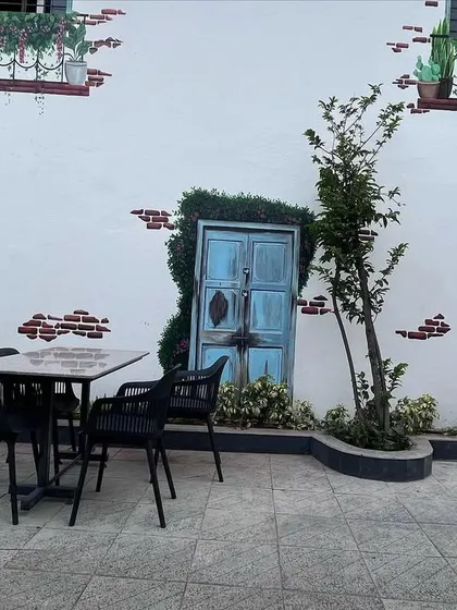 This pleasant and vibrant mural was for a large barn-style cafe. The painting of a European-style house front with brick details and a rustic door creates a charming, al-fresco dining atmosphere.