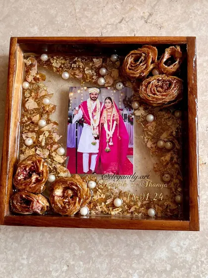 A lovely 8-inch teakwood frame preserving golden-hued roses from a wedding varmala. The simple arrangement allows the beauty of the flowers and the couple's photo to shine.