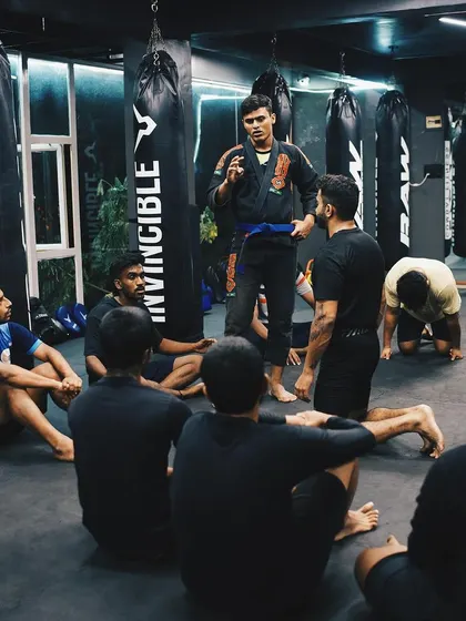 I lead a discussion with a group of students sitting on the mat, explaining a concept or technique.