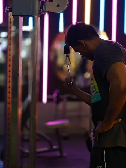 A client focuses on a tricep pushdown. The lighting and atmosphere of our gym are designed to get you into a focused, determined mindset.