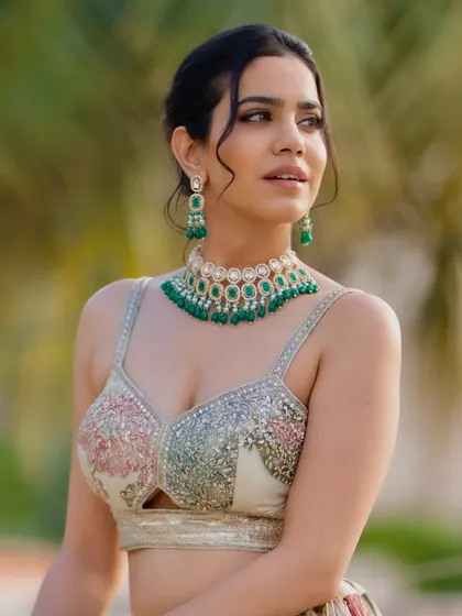 A close-up on the intricately embroidered blouse and the stunning green necklace, highlighting the details that make the look special.