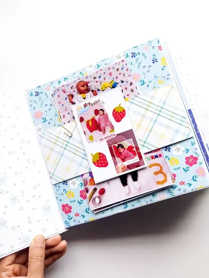 An interactive waterfall card in a baby scrapbook, perfect for showing monthly milestone photos from the first year.