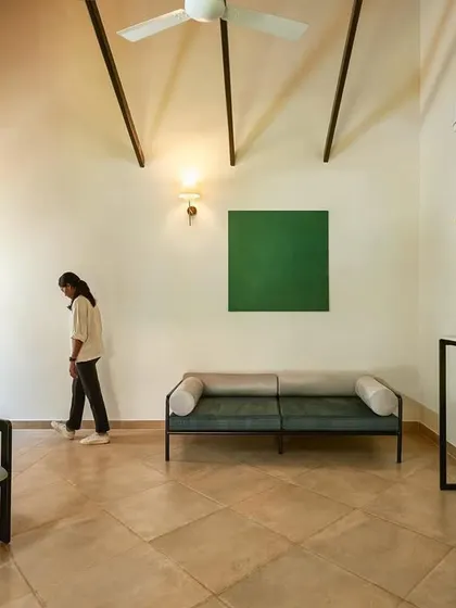 The living area of a guest suite, featuring minimalist furniture and a high ceiling. The space is designed to feel airy, calm, and uncluttered.