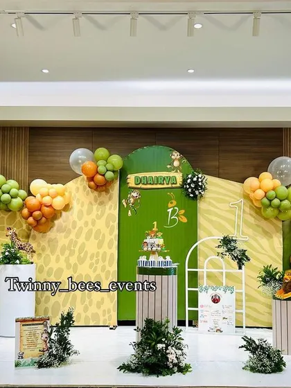 A wide shot of the grand jungle theme we created for Dhairya's first birthday. The stage setup includes multiple themed backdrops, balloon garlands, and plenty of greenery to create an immersive experience.