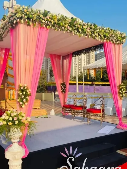 An outdoor mandap setup at a temple, perfect for a traditional wedding ceremony. The pink draping and floral arrangements create a beautiful sacred space.