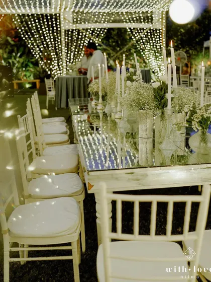A long view of the mirrored dining tables reflecting the canopy of lights. This setup creates a stunning visual effect, making the dining experience feel incredibly special and immersive.