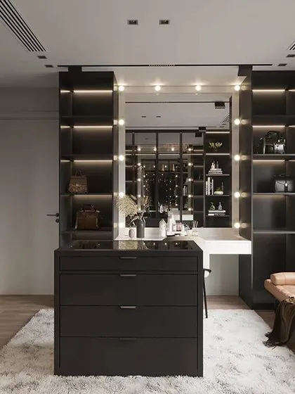 A high-end dressing room with open, back-lit shelving and a central drawer island. The Hollywood-style vanity mirror provides perfect lighting for getting ready.
