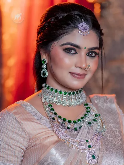 A close-up portrait focusing on the beautiful green-stoned choker and the matching maang tikka.