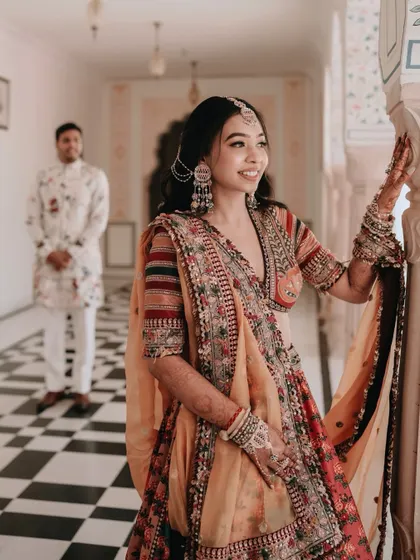 The bride, in her colorful Haldi outfit, looks on as the groom stands in the background, creating a beautiful portrait with a sense of depth and story.