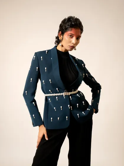 A powerful and chic pose showcasing an embellished blazer. The styling is modern and sophisticated, perfect for a contemporary luxury brand.