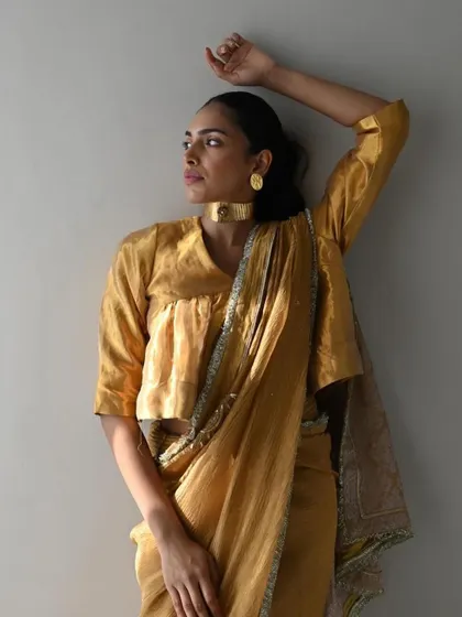 A simple yet stunning golden chanderi saree. The beauty of this look is in its understated elegance, paired with a statement choker to create a sophisticated and modern ensemble.