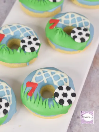 Baked donuts decorated for a football party. We added a soccer net design, edible grass, and the birthday boy's age to tie everything into the theme.